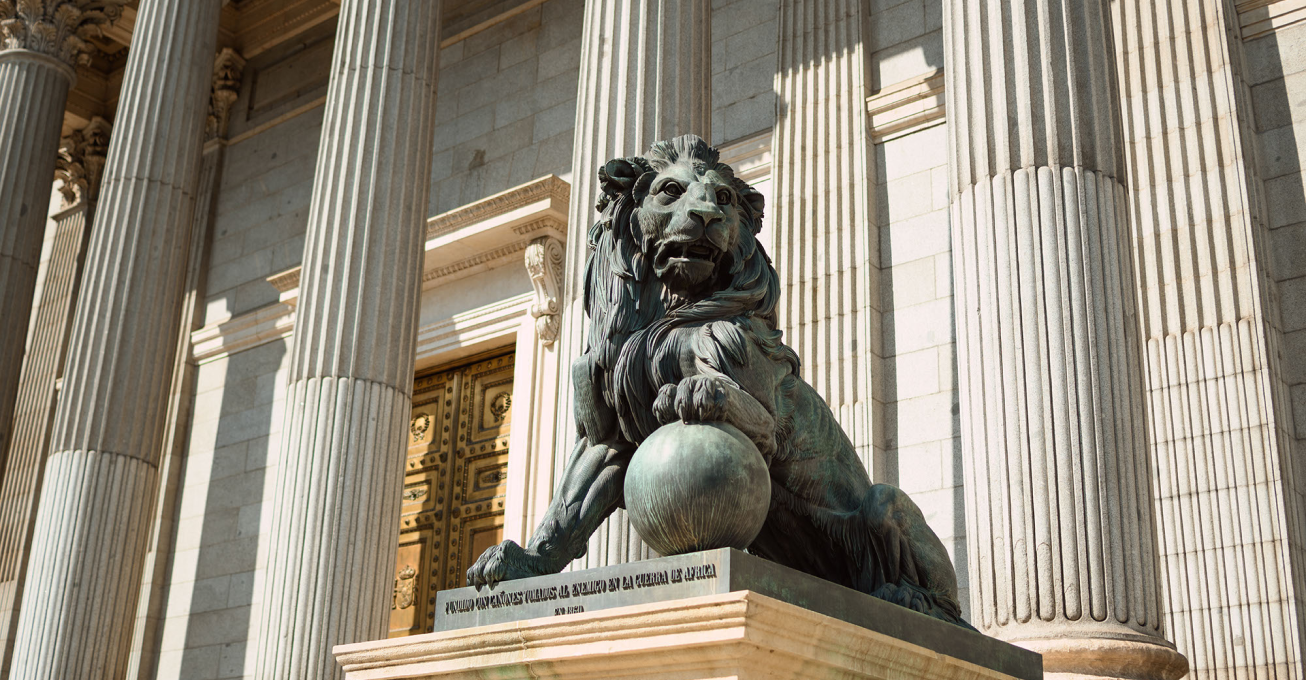 A stock photo of a stone lion outside of a building with marble columns