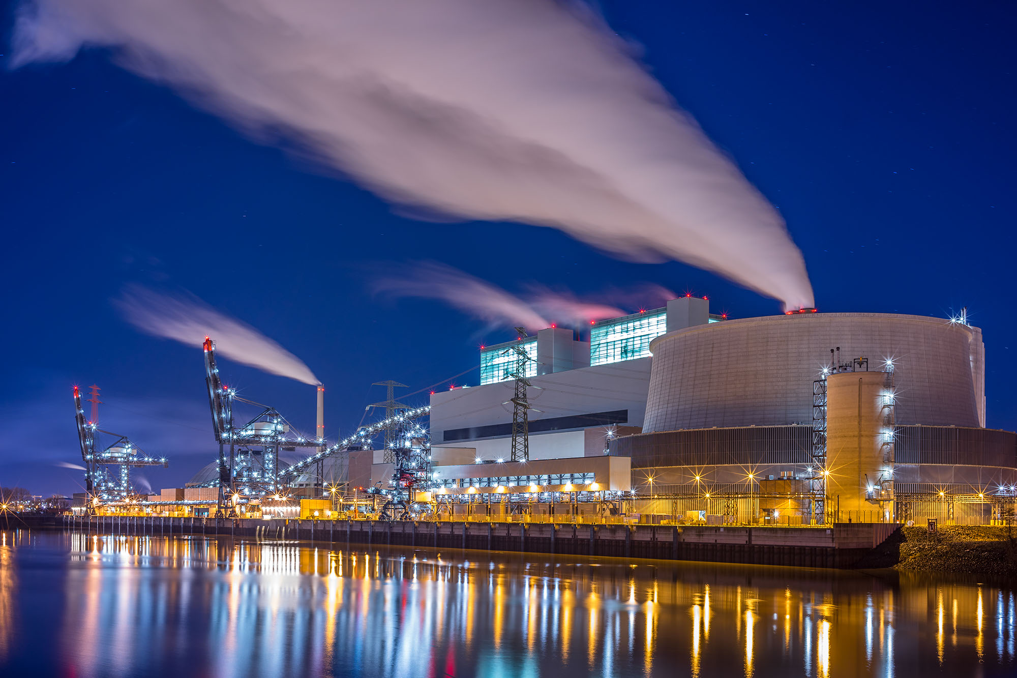 A stock photo of a coal fired power plant on a body of water at night
