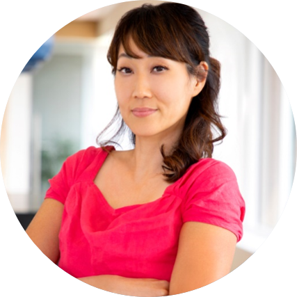 Smiling Asian woman in a red top, arms crossed.